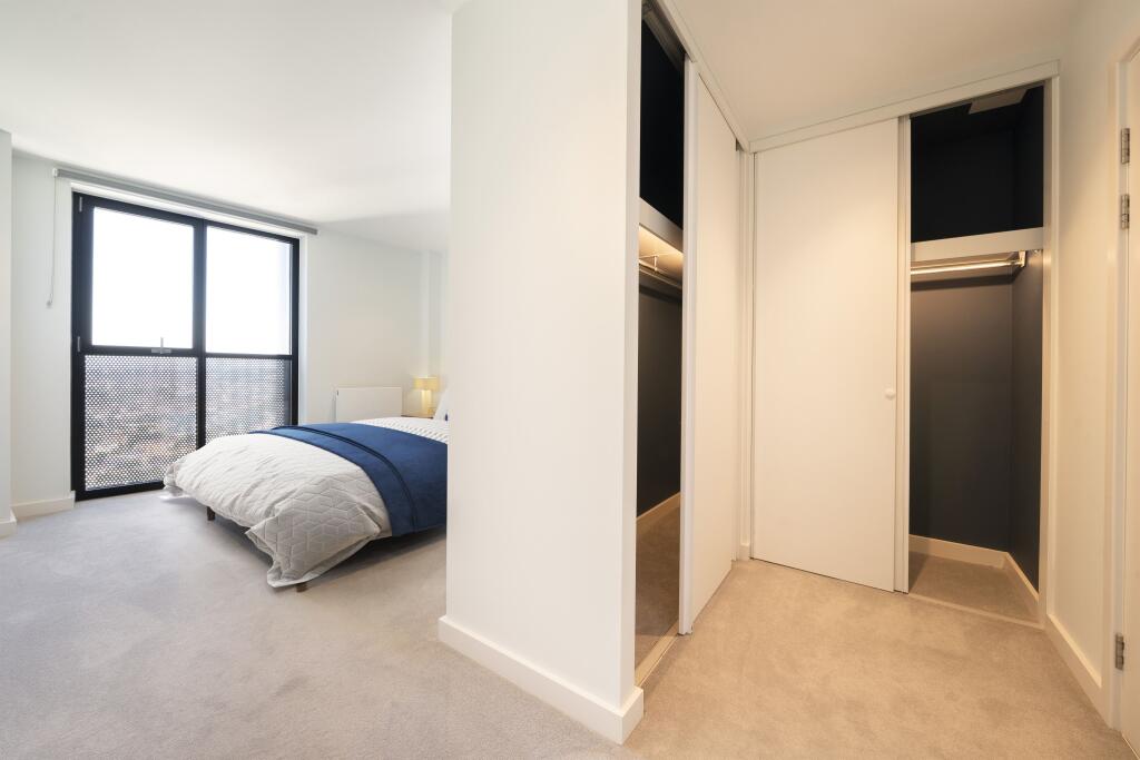 Experience luxury in this modern bedroom with ample natural light and a spacious closet.