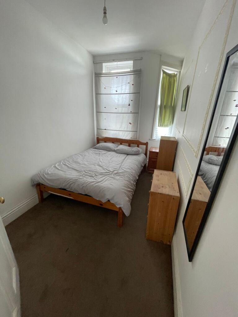 A cozy single bedroom featuring a wooden bed fr...