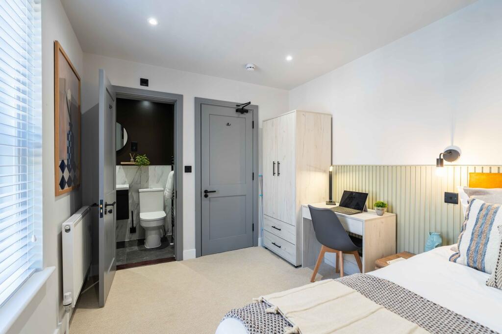 A modern and well-lit student bedroom featuring...