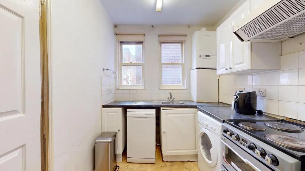A compact kitchen featuring modern appliances i...