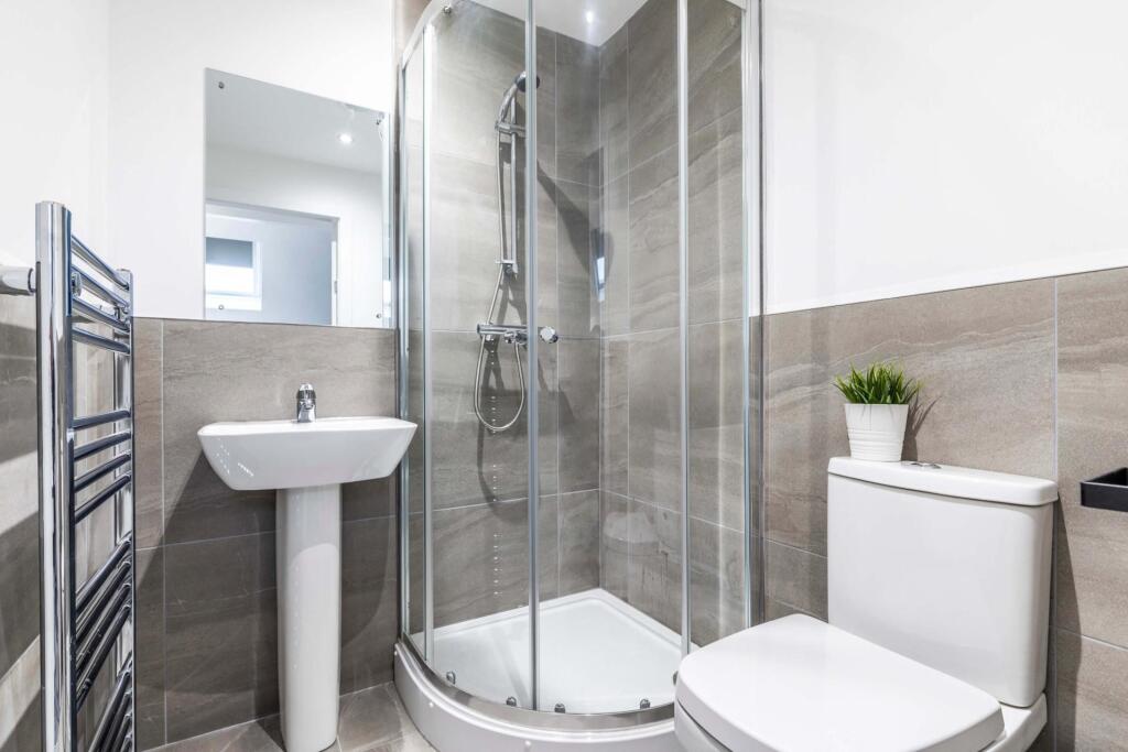 Modern, well-kept bathroom with a curved glass ...
