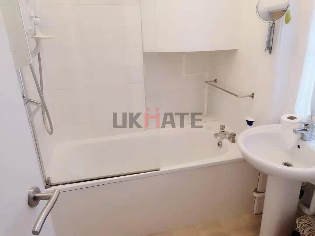 Bright and clean bathroom featuring a bathtub w...