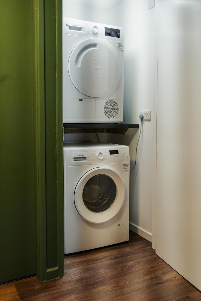 A compact laundry area featuring stacked washin...