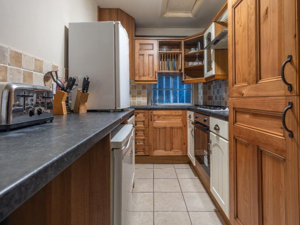 A warmly lit kitchen featuring wooden cabinetry...