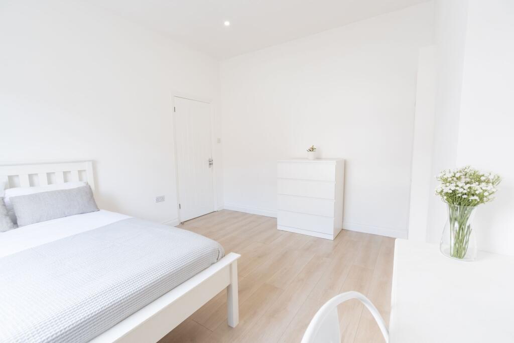 Bright, airy bedroom with white walls and moder...