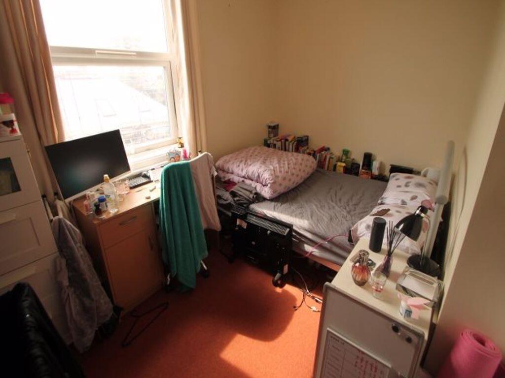 A cozy single bedroom featuring a large window ...