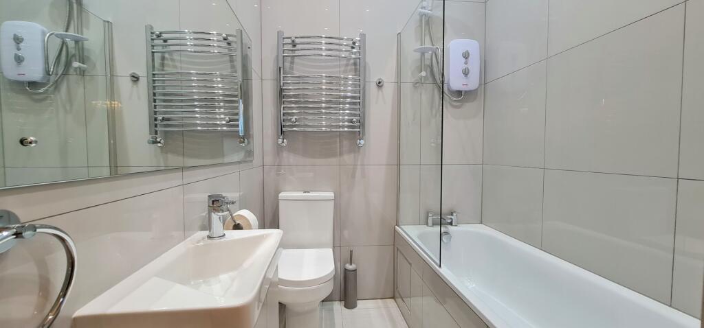 A clean and modern bathroom featuring a bathtub...