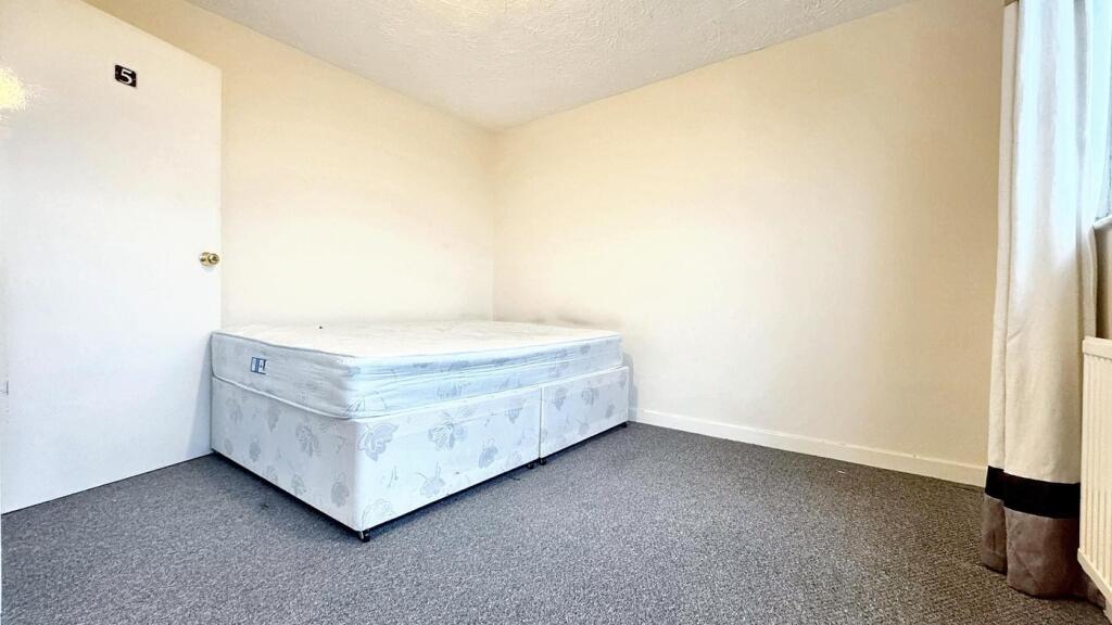 Spacious double bedroom featuring a fresh, neut...