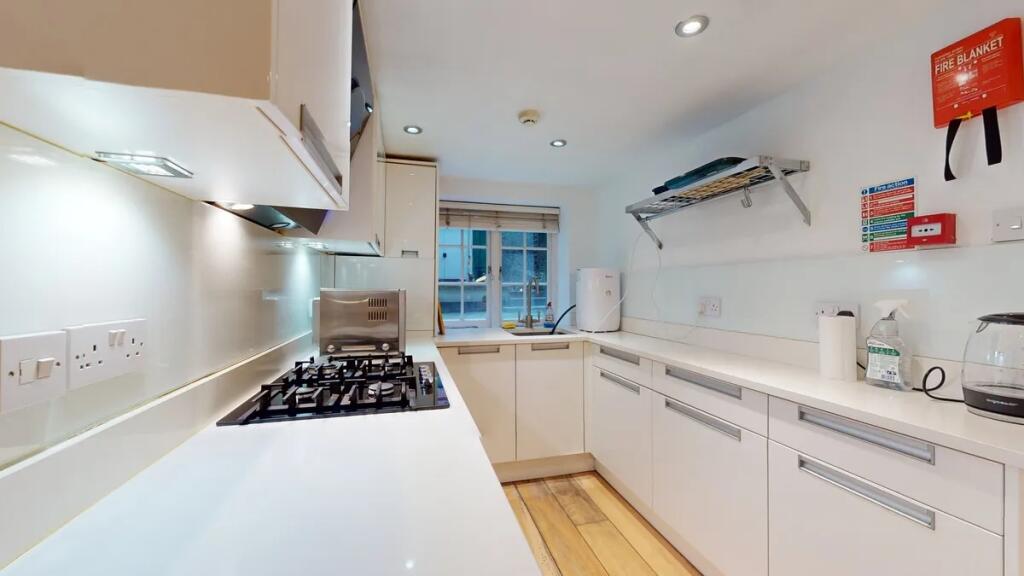 A modern, sleek kitchen featuring white cabinet...