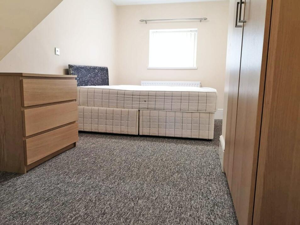 A neat and tidy single bedroom featuring a comf...