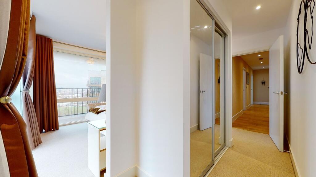 A bright and clean hallway with beige carpeting...