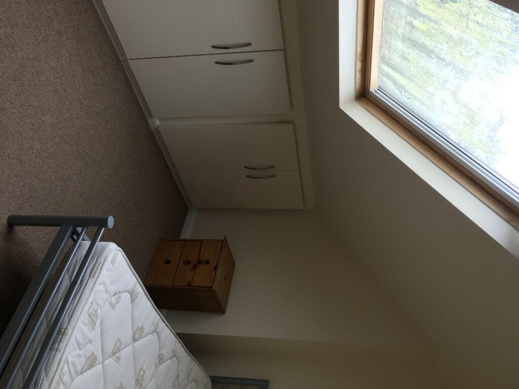 A small single bedroom featuring a large skylig...