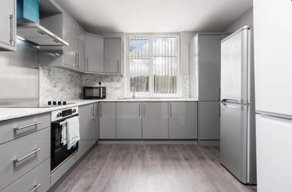 This modern kitchen features sleek grey cabinet...