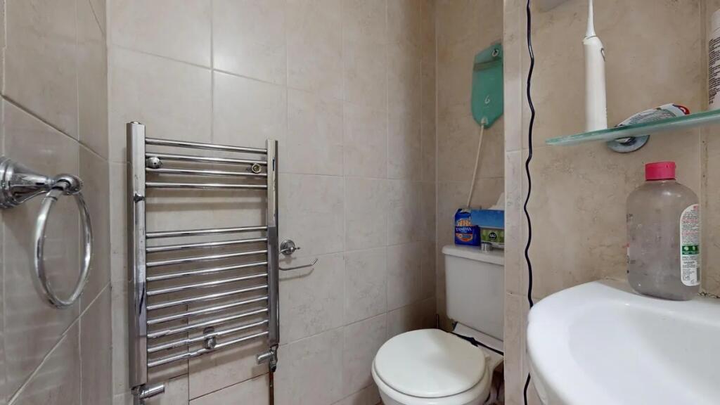 A compact and clean single toilet room featurin...