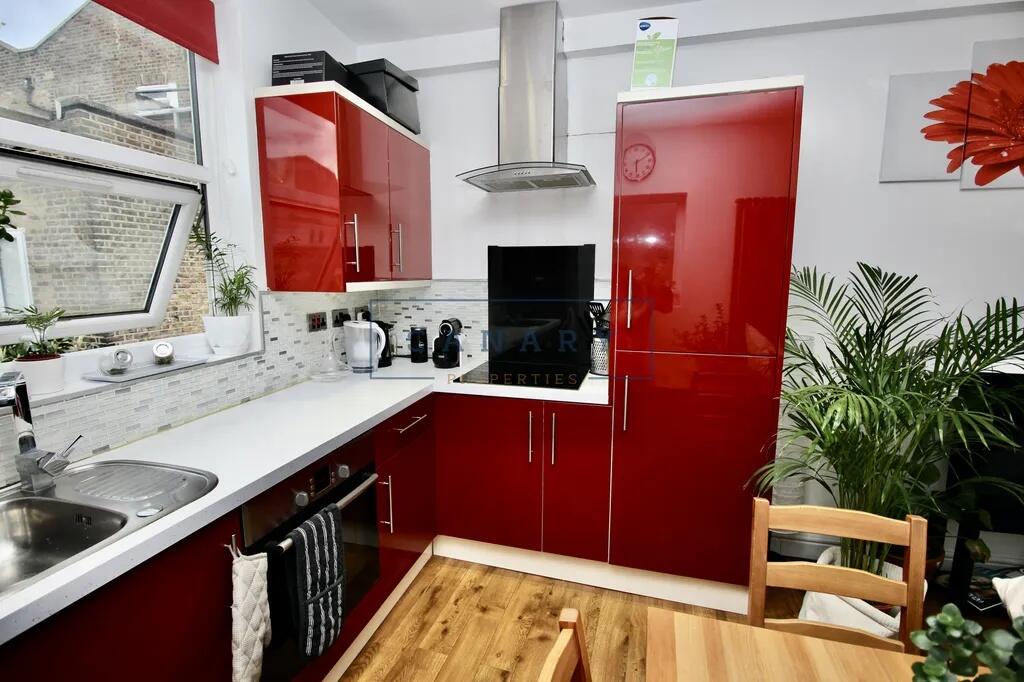 Modern kitchen with glossy red cabinetry, brigh...
