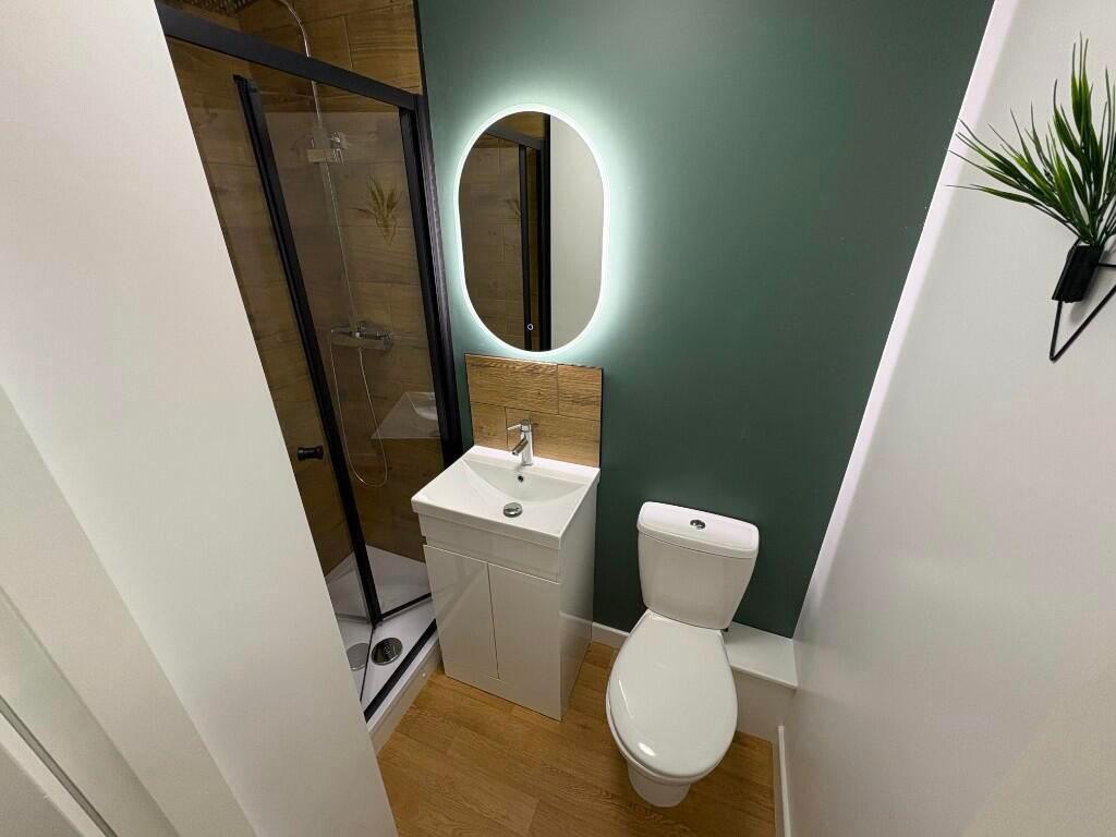 A modern bathroom featuring a glass-enclosed sh...