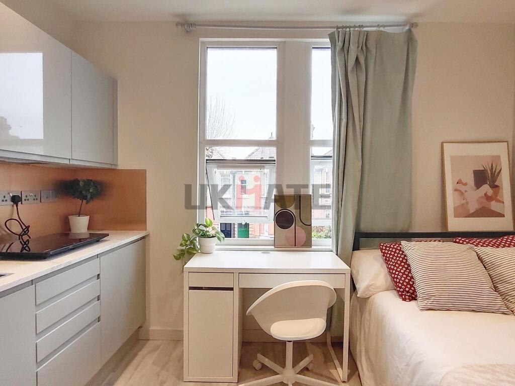 A cozy single bedroom featuring a bed with stri...