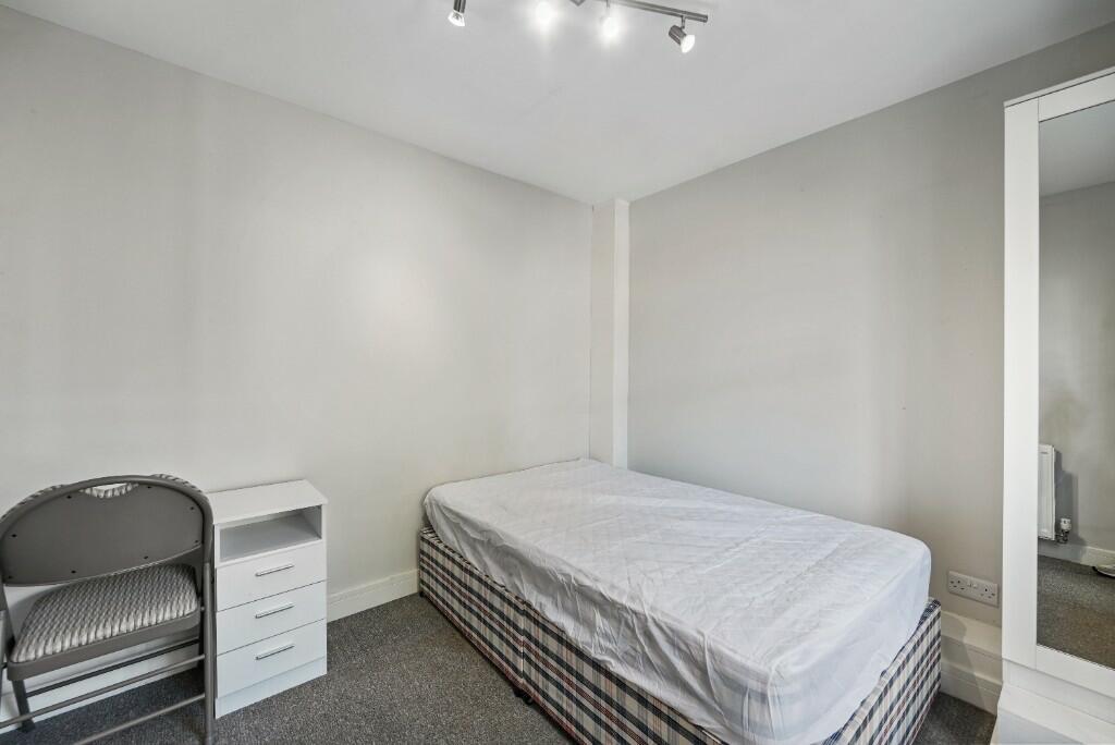 A tidy single bedroom featuring a simple bed wi...