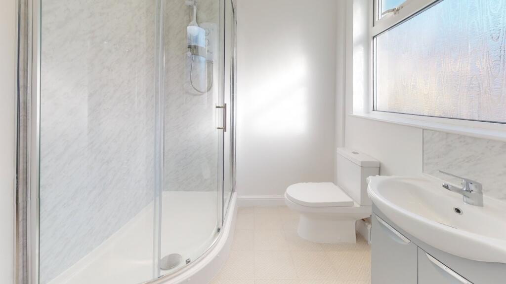 Bright, modern bathroom featuring a glass showe...
