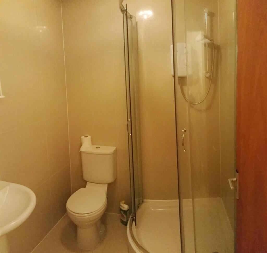 Compact, clean bathroom with a modern corner sh...