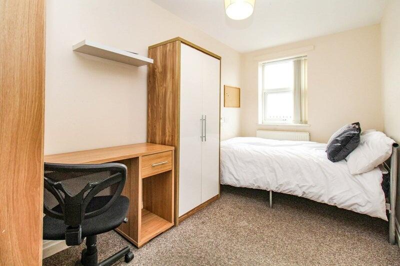 A clean and inviting single bedroom featuring a...