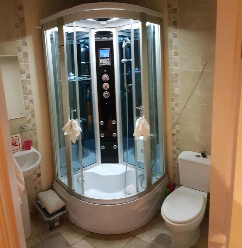 A modern bathroom suite featuring a curved glas...