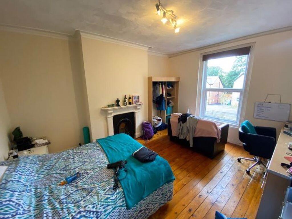A bright double bedroom featuring wooden floors...