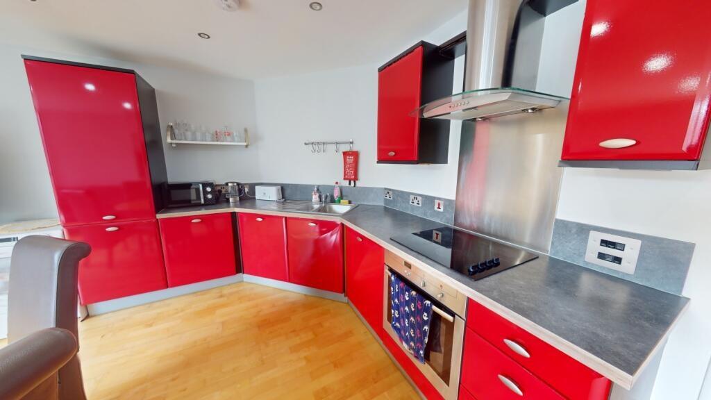 Modern kitchen with vibrant red cabinetry, slee...