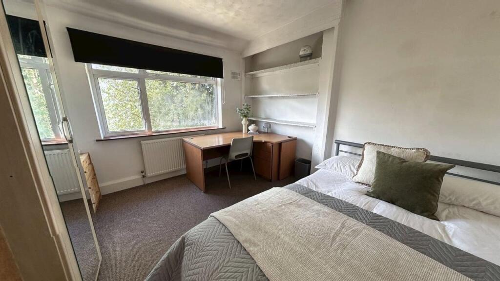 A cozy student bedroom featuring a neatly made ...