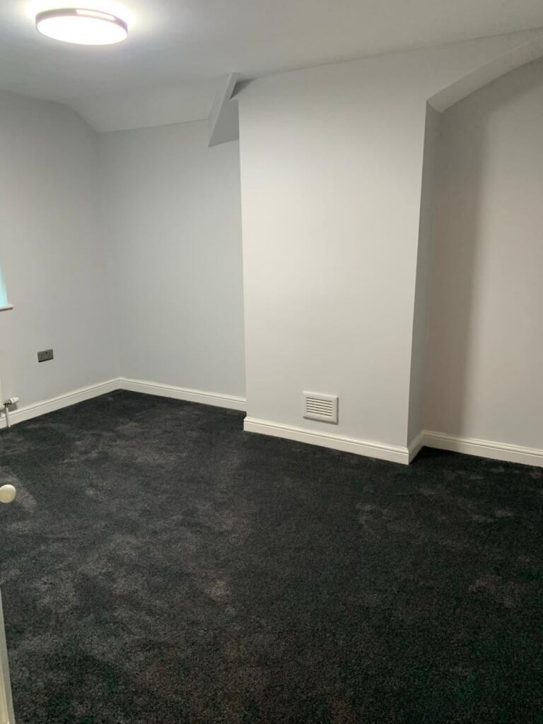 A clean and simple single toilet room with dark...