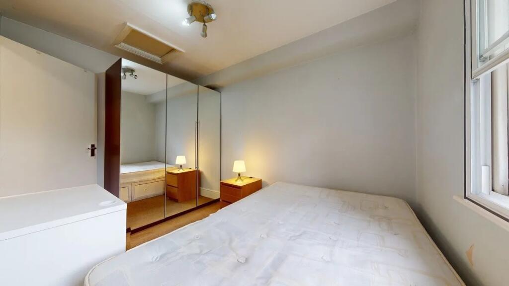 A cozy double bedroom featuring a large bed, mi...