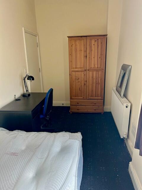 A cozy single bedroom featuring a wooden wardro...