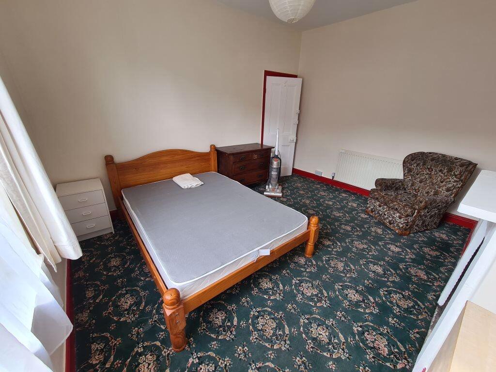 A cozy double bedroom featuring a wooden bed fr...