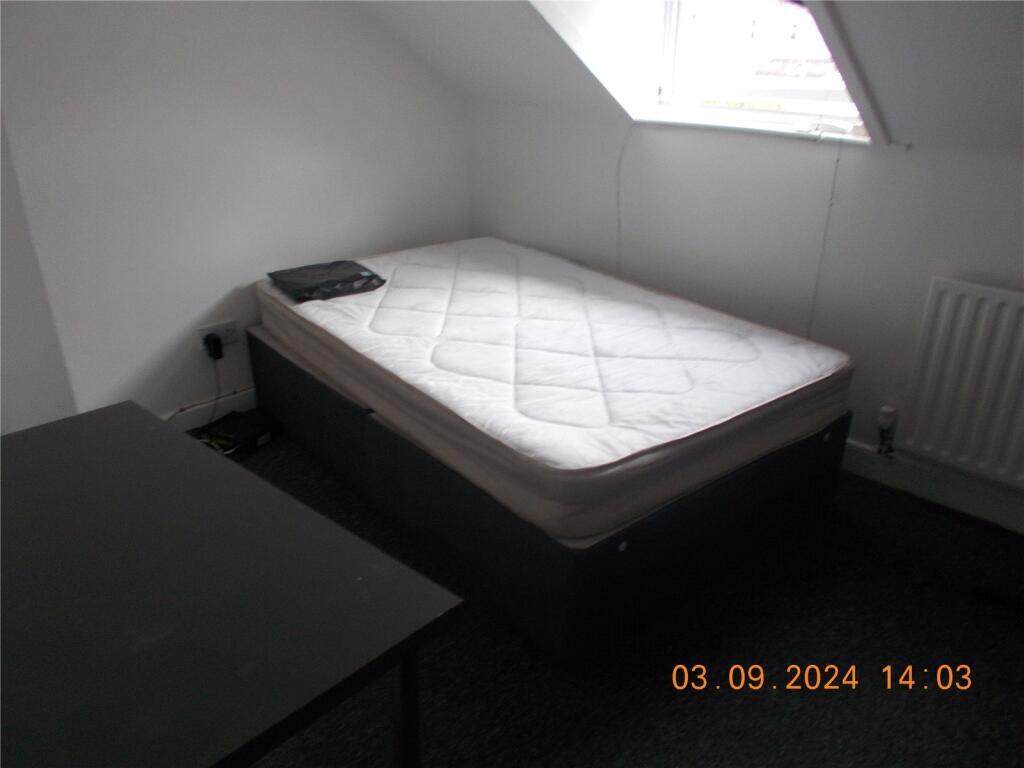 A simple, tidy single bedroom featuring a mattr...