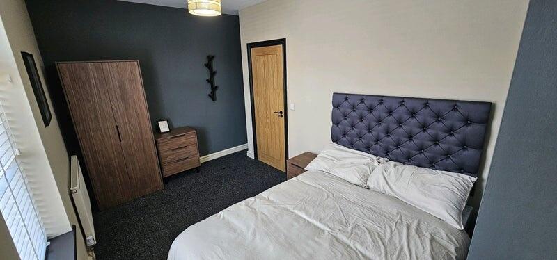 A cozy double bedroom featuring a tufted headbo...