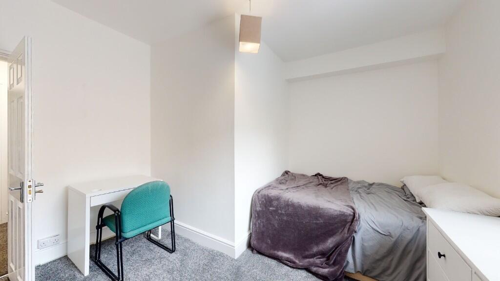 A neat and cozy single bedroom featuring a comf...