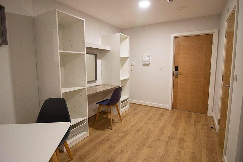 A clean, modern hallway with wooden flooring, b...