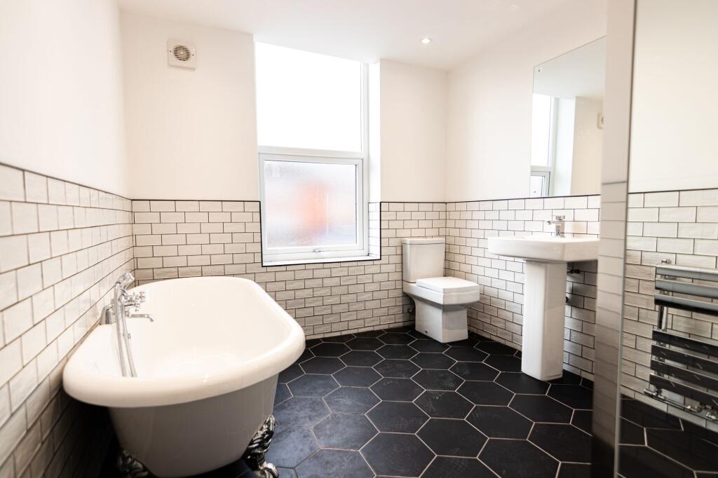 A spacious bathroom featuring a classic free-st...