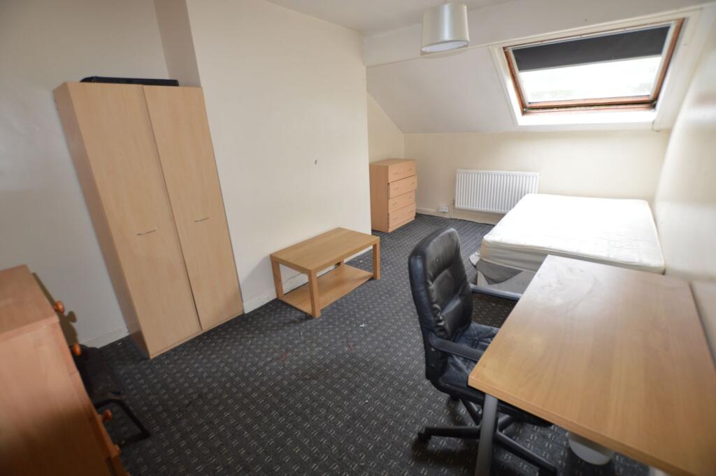 A cozy single bedroom featuring a slanted skyli...