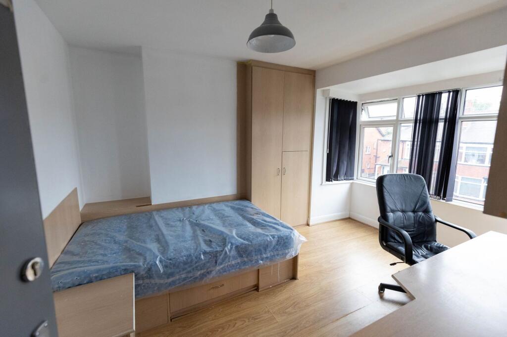 A bright single bedroom featuring a bed with a ...