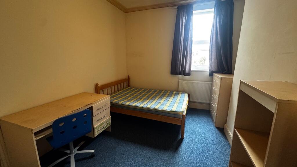 A modest bedroom featuring a single bed with a ...