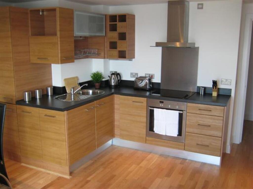 A modern kitchen with wooden cabinetry and blac...