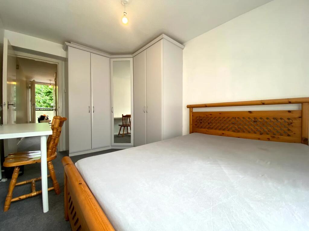 A bright and tidy bedroom featuring a wooden be...