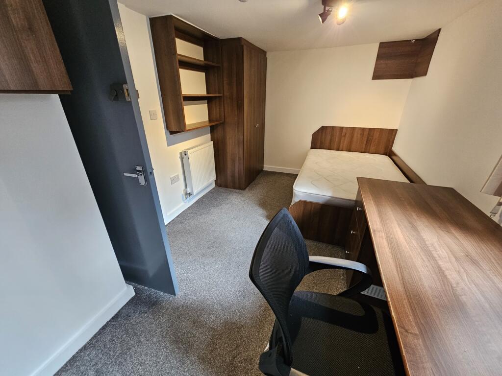 A neat and functional student bedroom featuring...