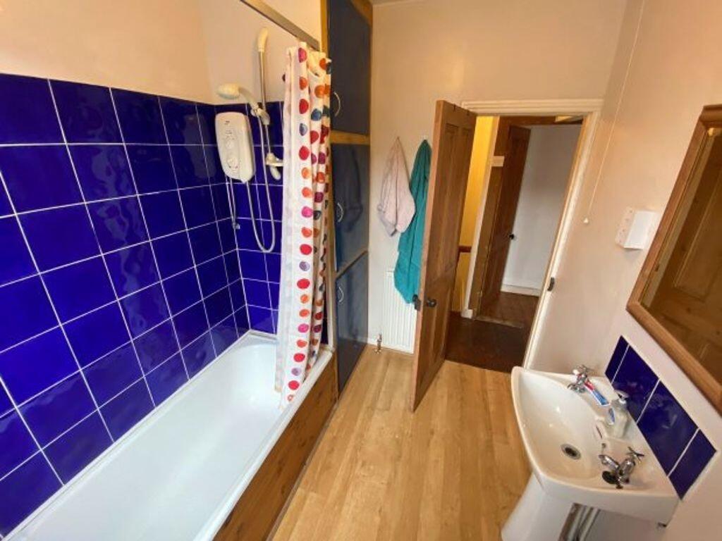 Bright, clean bathroom with modern blue tiled s...