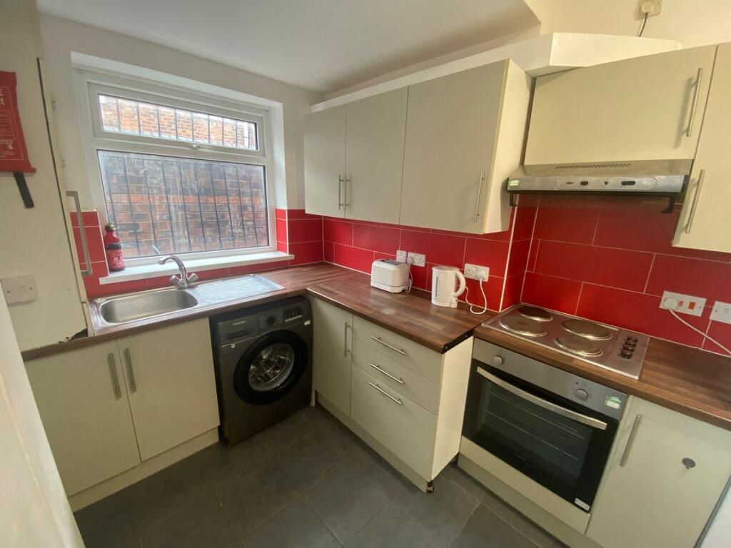A compact, modern kitchen featuring clean white...