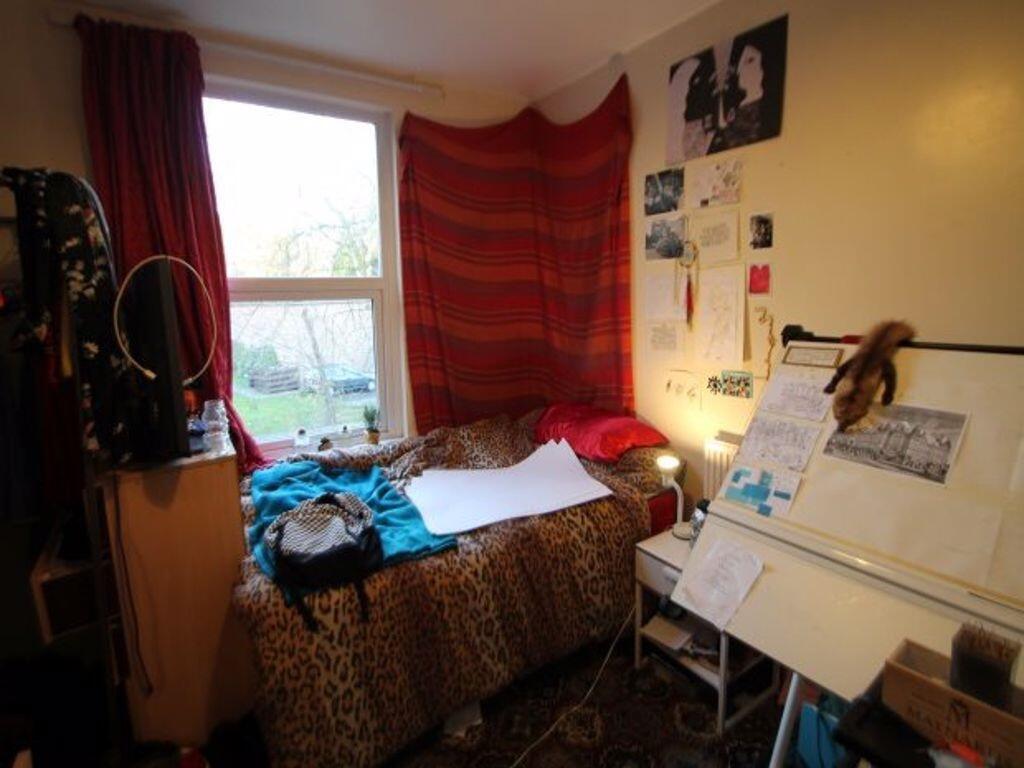 A cozy single bedroom with a large window allow...
