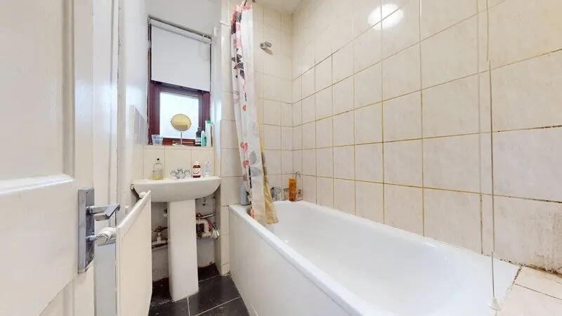 A tidy bathroom featuring a white bath with a p...