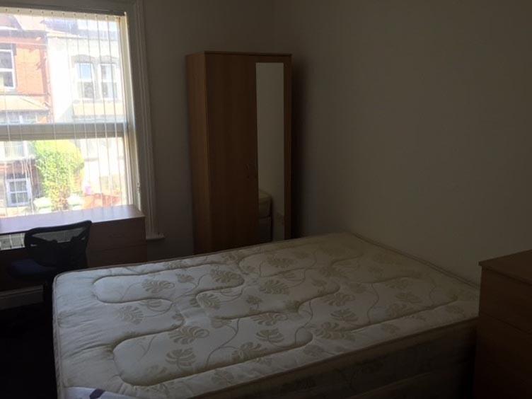 A modest bedroom with a double bed frame and a ...