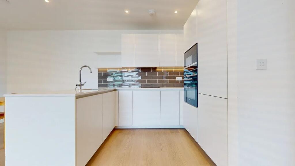 Modern kitchen featuring sleek white cabinets, ...